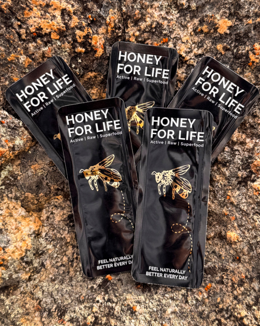Ten packets of honey with branding 'HONEY FOR LIFE' displayed on a natural stone surface.