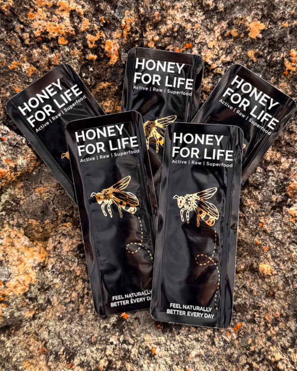 Ten packets of honey with branding 'HONEY FOR LIFE' displayed on a natural stone surface.