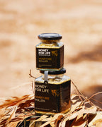 Two jars of 'Honey for Life' honey bee pollen on a blurred natural background