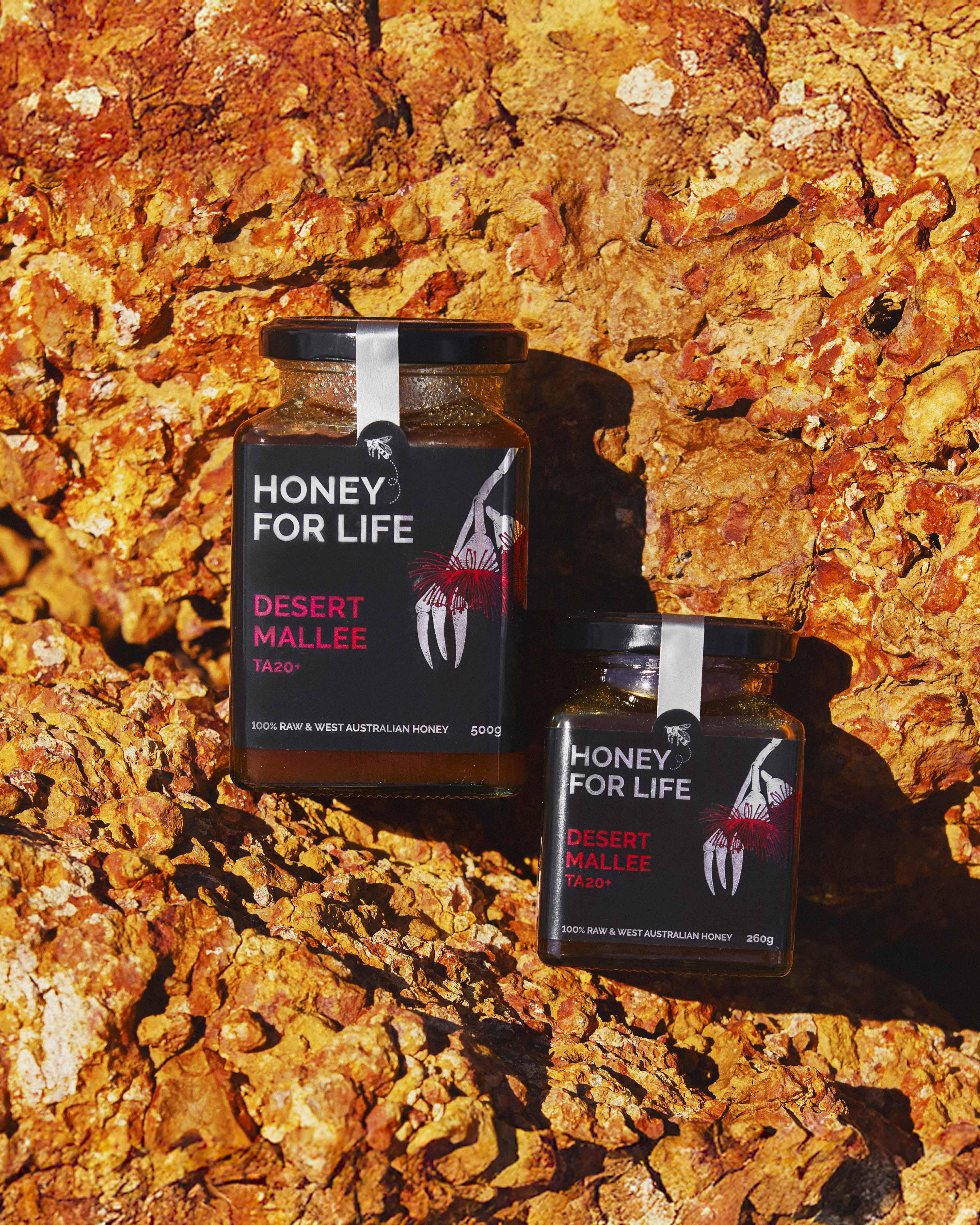 Two jars of 'Honey for Life' desert mallee honey on a textured rock background