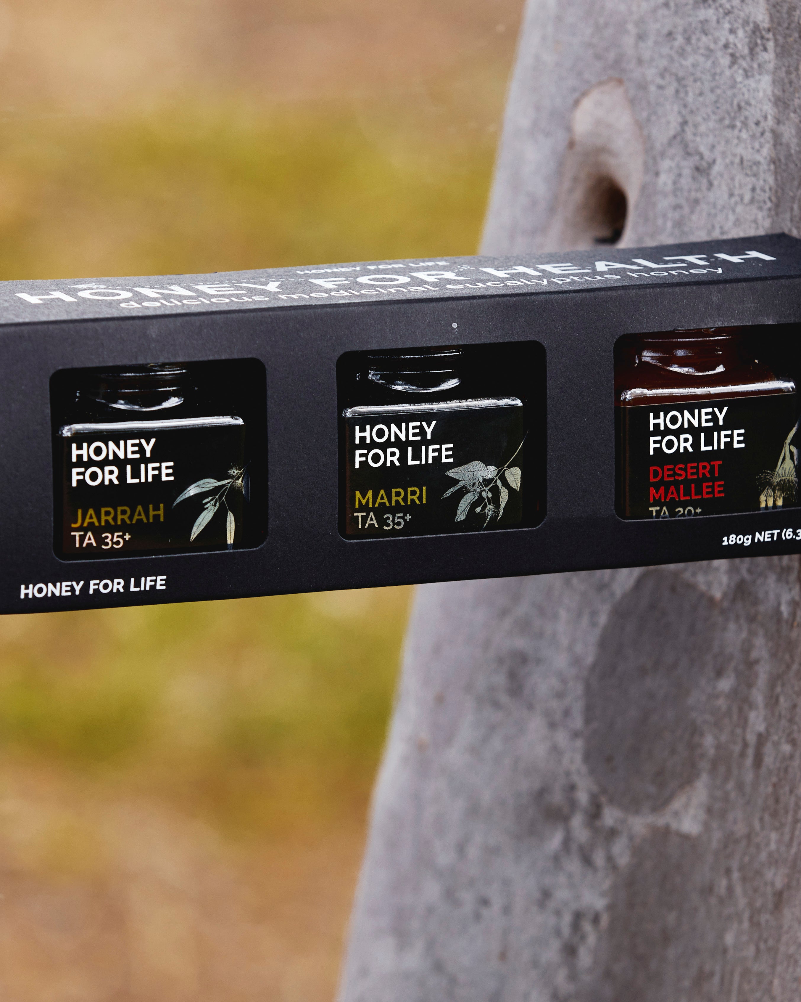 Packaging of 'Honey for Life' honey with tree in the background