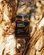 Jar of 'Honey for Life' jarrah honey against a tree bark background