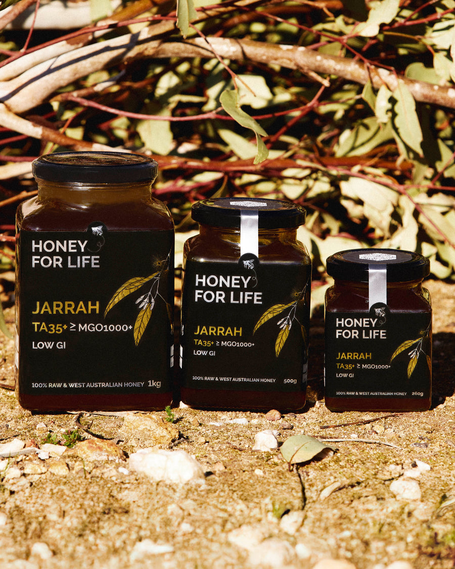 Three jars of 'Honey for Life' jarrah honey on a natural background with leaves and branches.