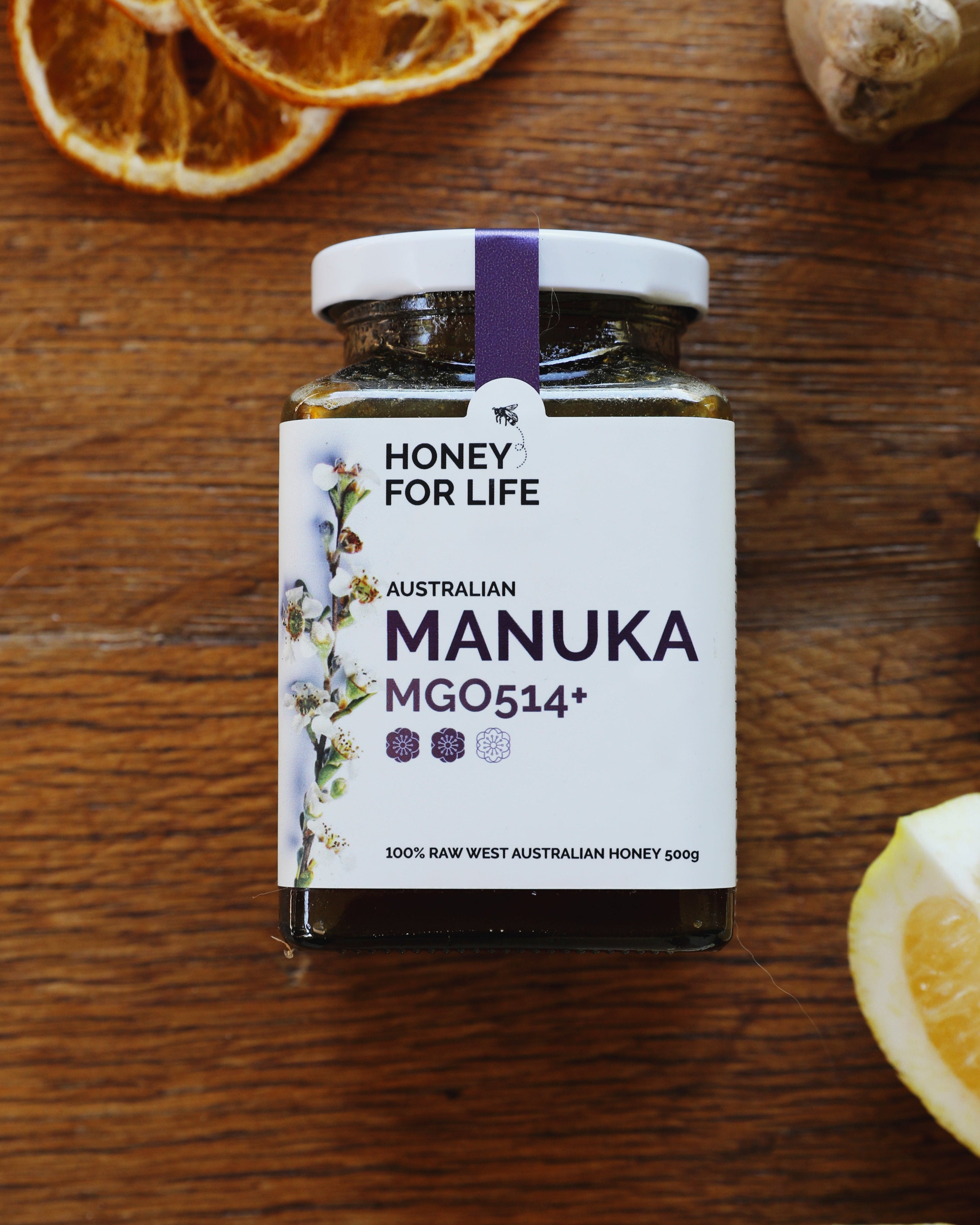 Manuka honey jar with lemons and dried oranges on a wooden surface