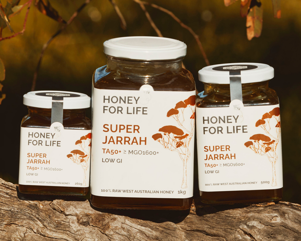 Three jars of 'Honey for Life' on a wooden log with a natural background