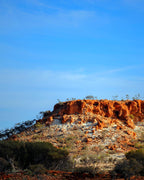 Red rock formation with sparse vegetation under a clear blue sky